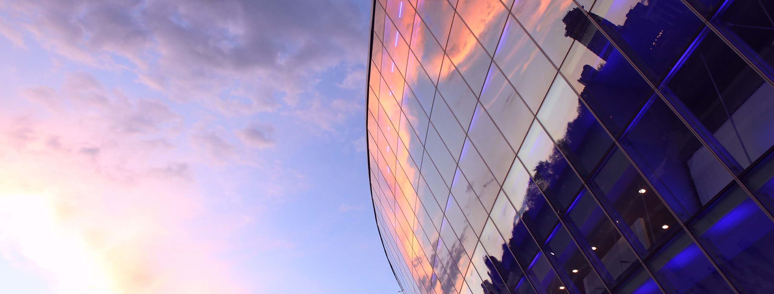 modern glass building with reflection of sky and clouds